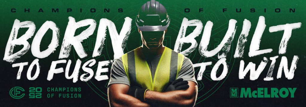 A worker in a hard hat and safety vest stands confidently with crossed arms. The text reads: Born to fuse. Built to win. Champions of Fusion. 2022. McElroy. The background features a green, industrial design.