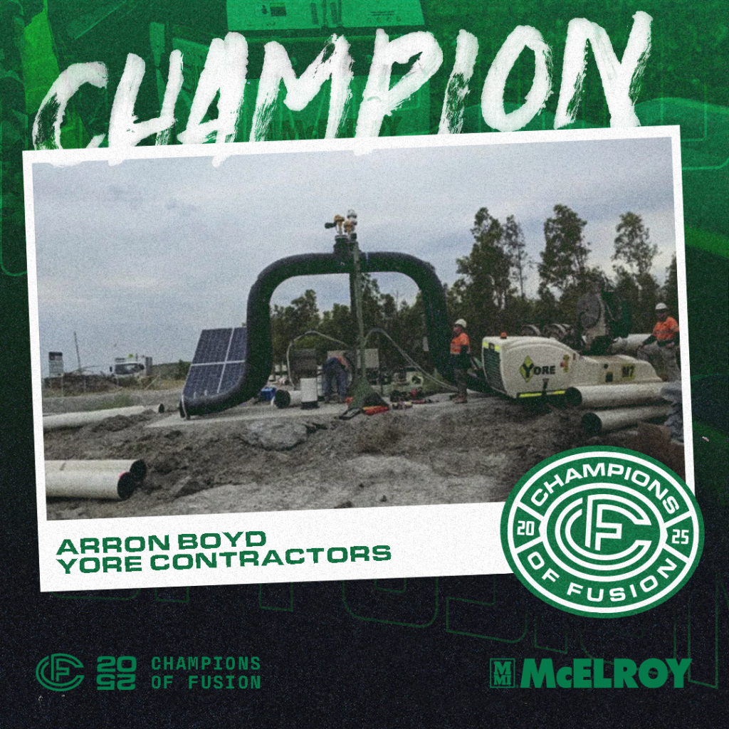 A construction team works outdoors with green industrial pipes and equipment. Text reads Champion, Arron Boyd Yore Contractors, Champions of Fusion 2023, and McElroy. Trees and cloudy skies are in the background.